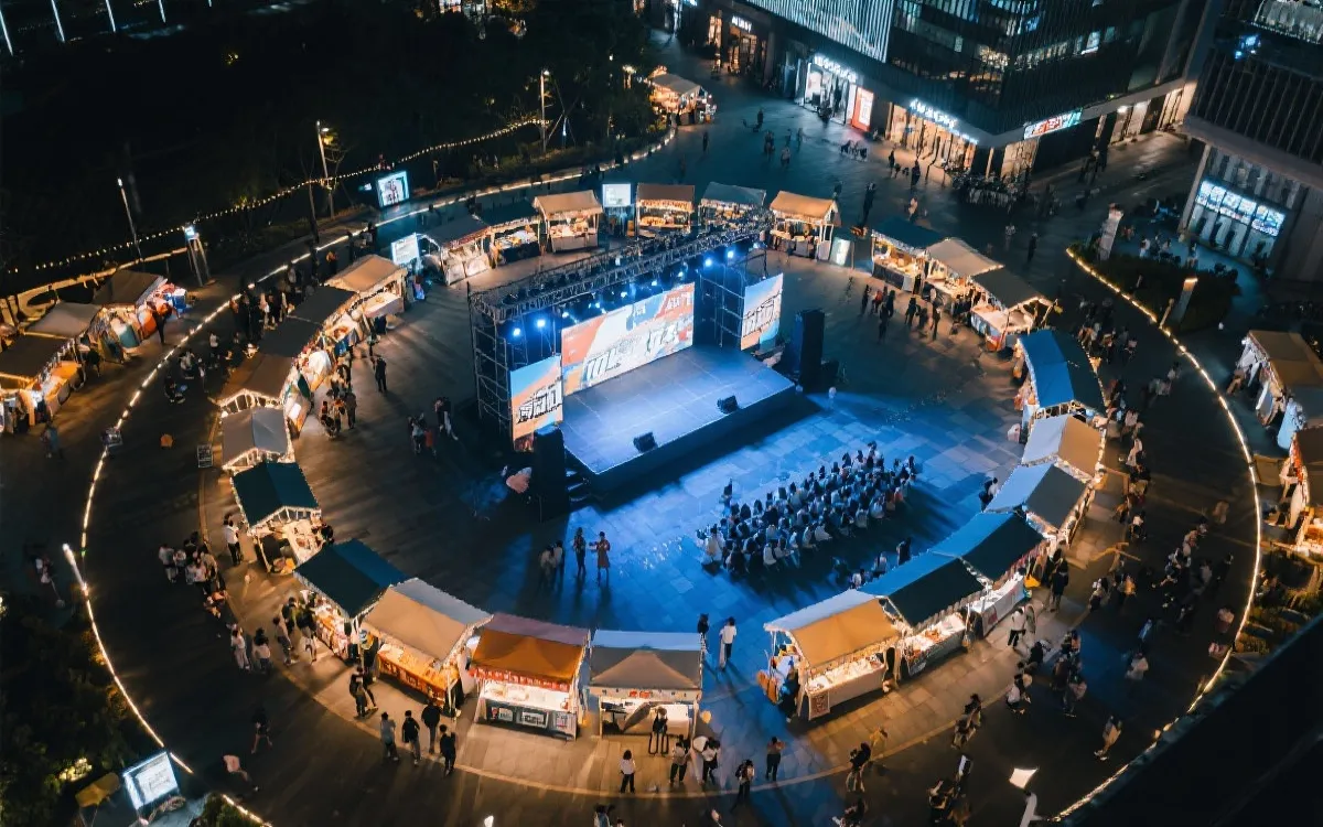 公共观赛区的夜间市集动线示意，摊位、舞台与大屏形成环形布局，氛围灯光
